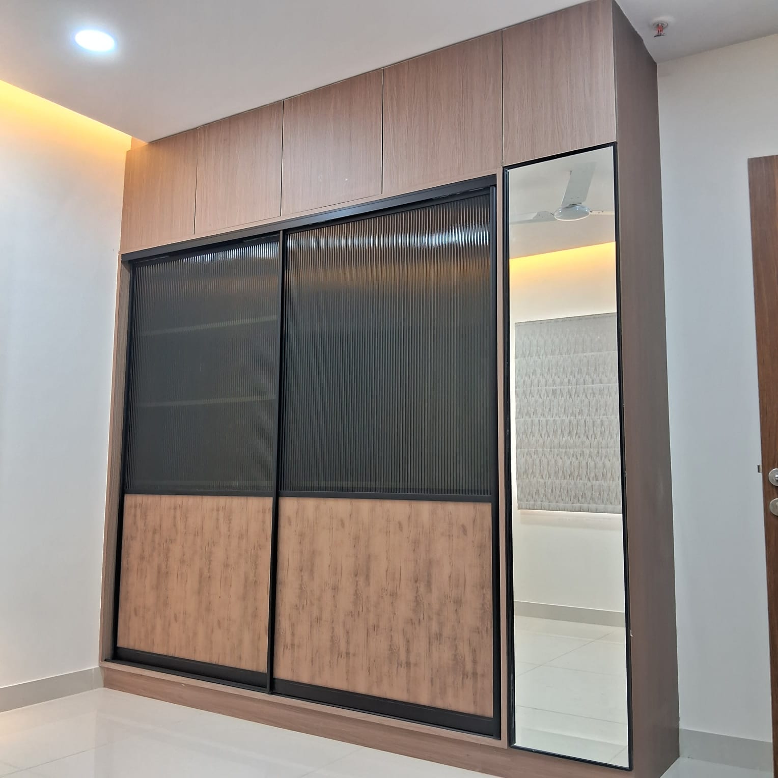 Bedroom sliding wardrobe with fluted glass panels and mirror