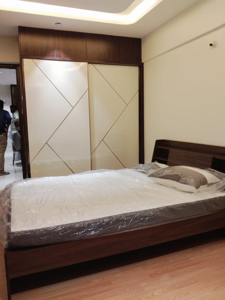 Cream and walnut angular-pattern sliding wardrobe beside a bed