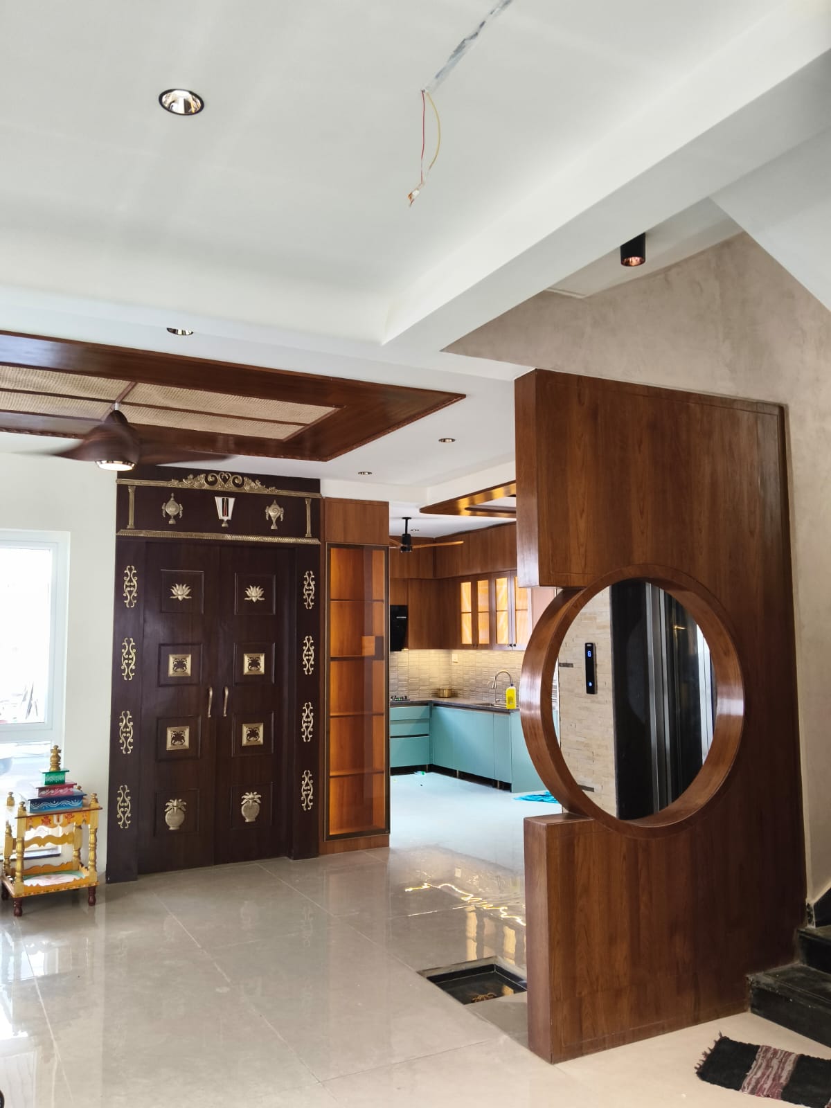 Brass-detailed wood pooja unit and entry foyer with round mirror feature